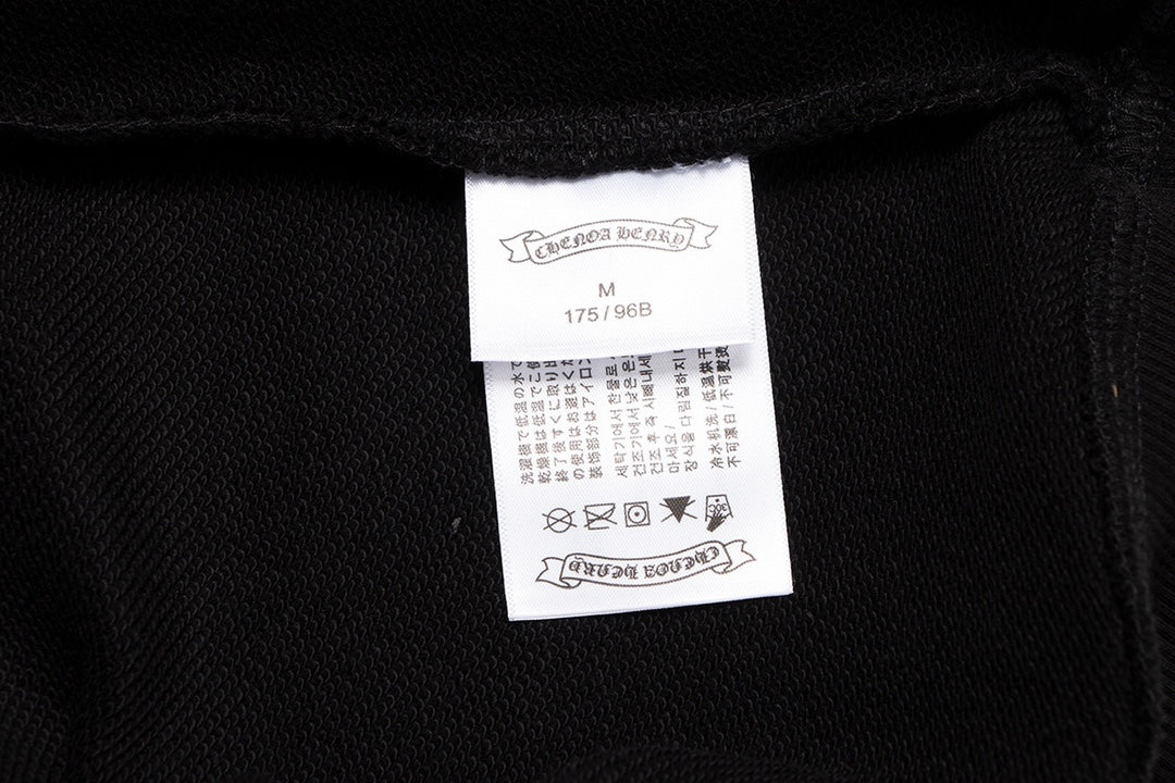 Sweat-shirt noir à motif de cœurs chromés, coulures de peinture et croix jaune.